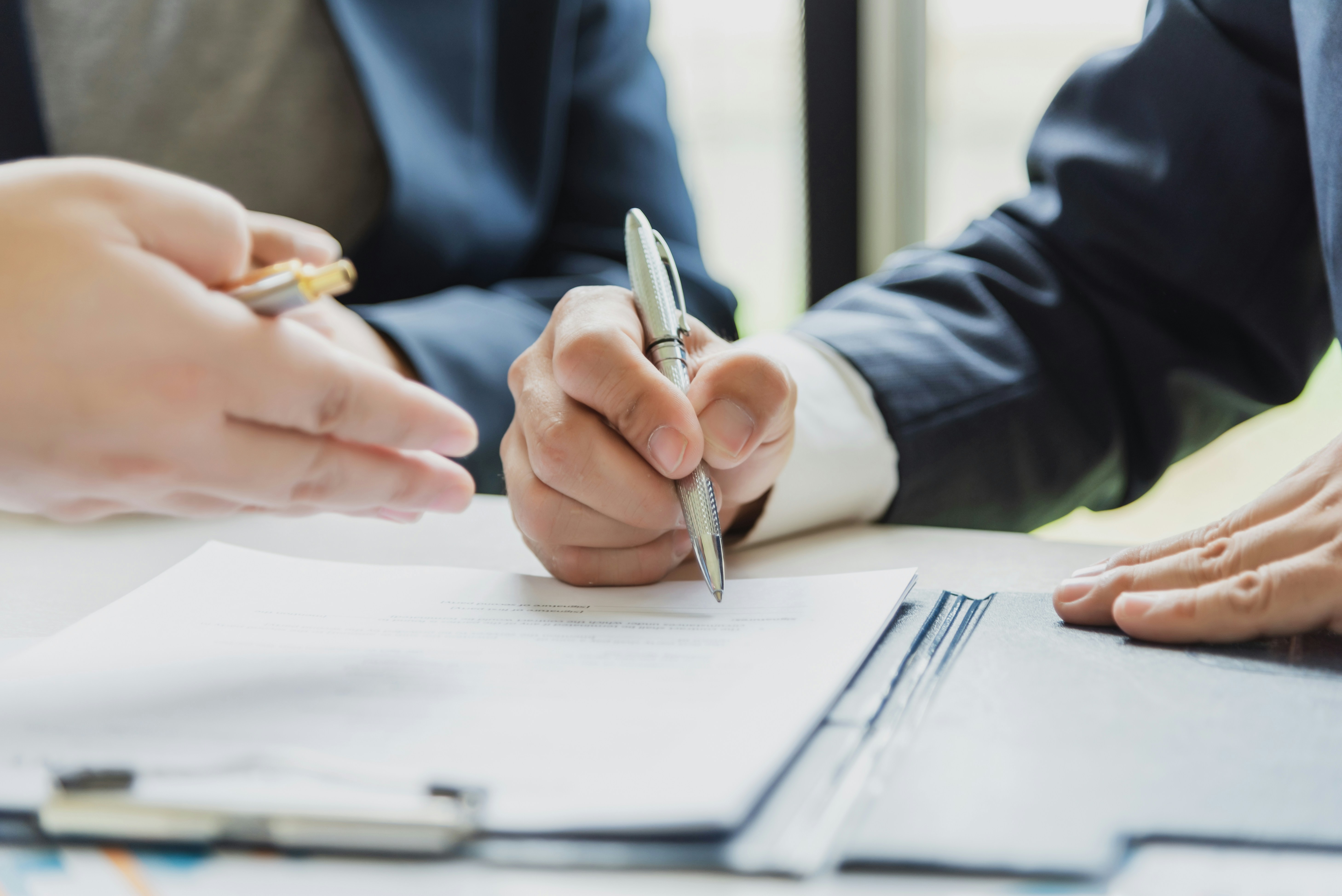 Two people reviewing and signing a document at a desk.