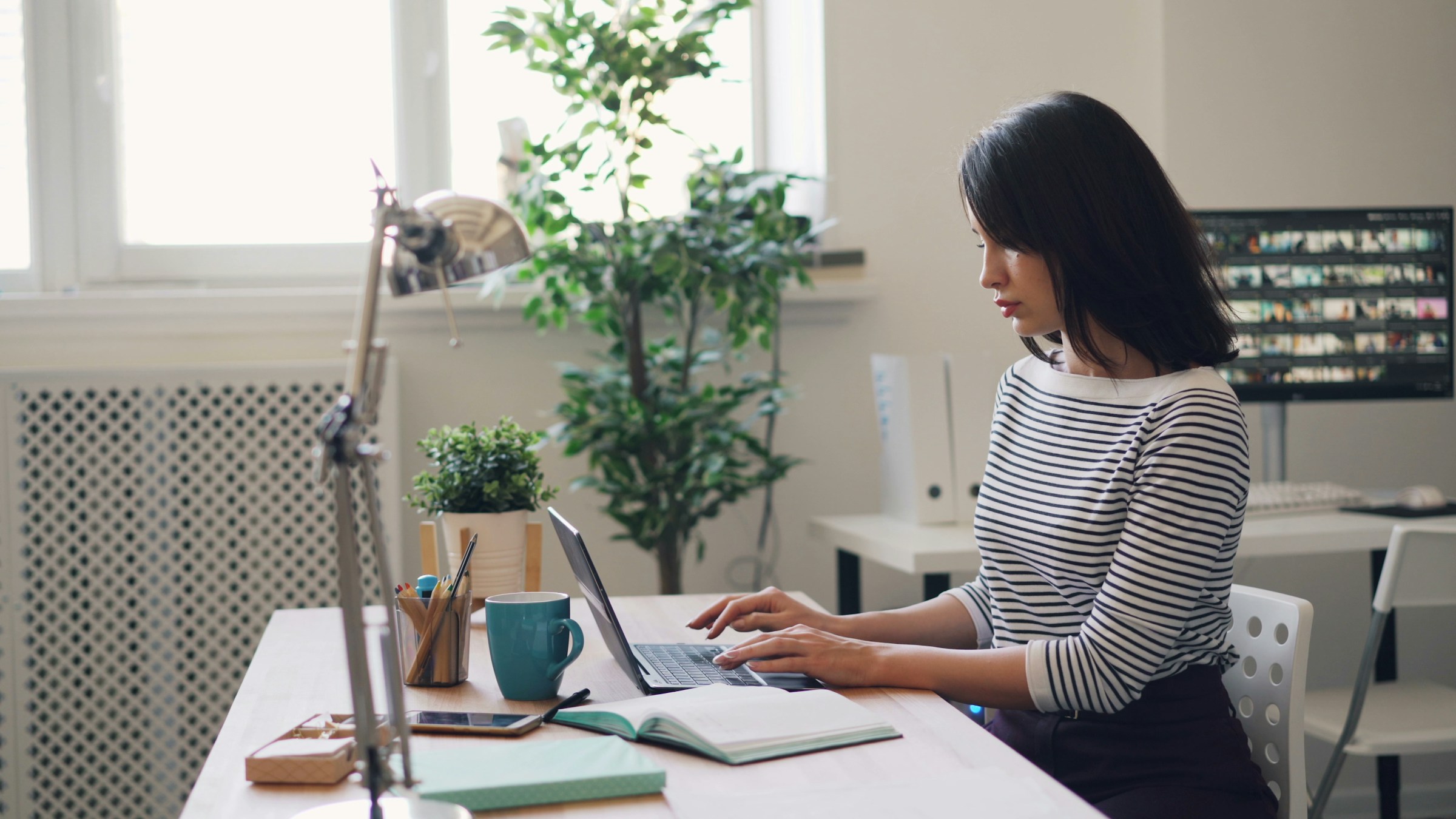 Woman working on a laptop at a desk in a home office setting