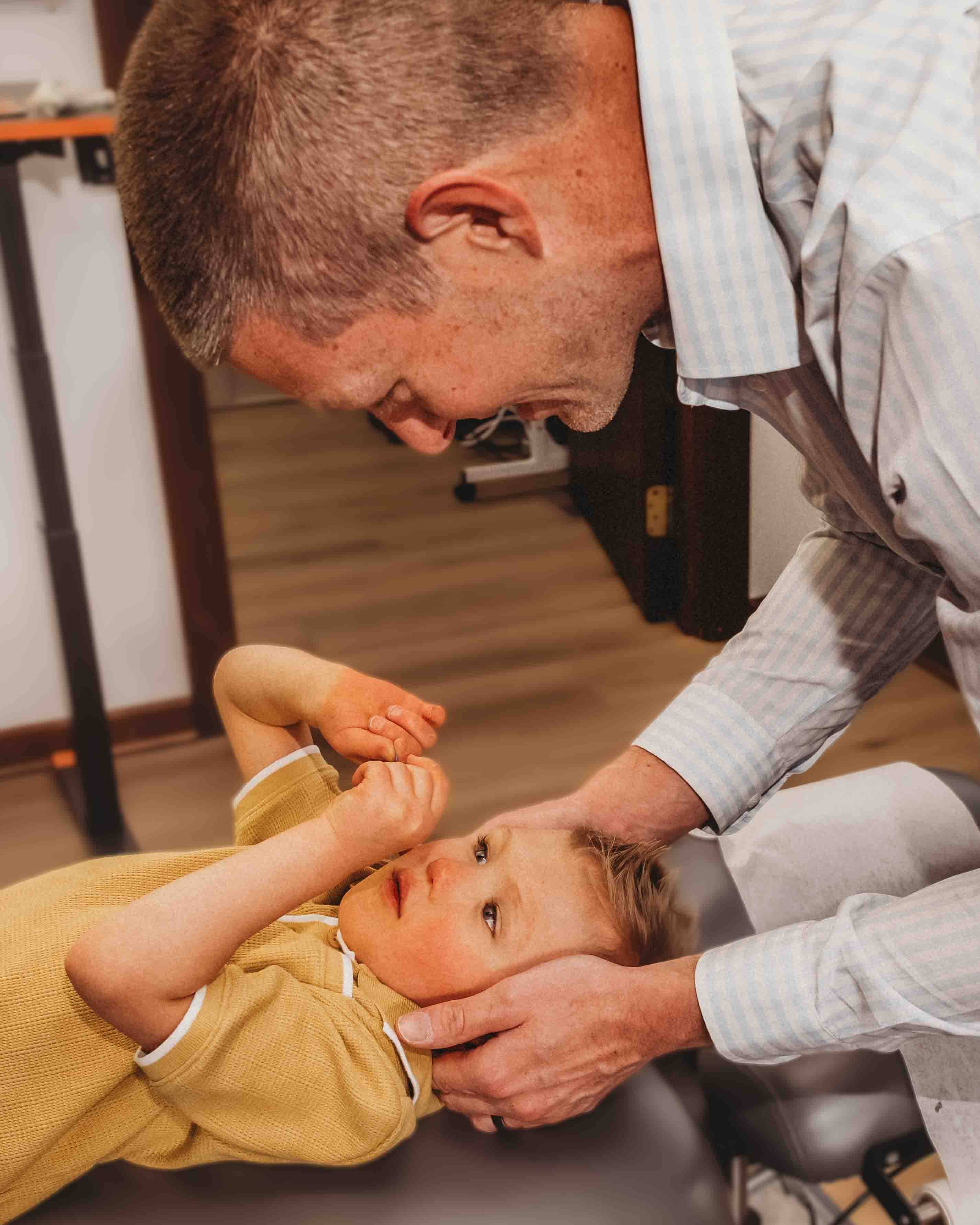 Physical therapist gently examining a patient’s neck and shoulder from behind