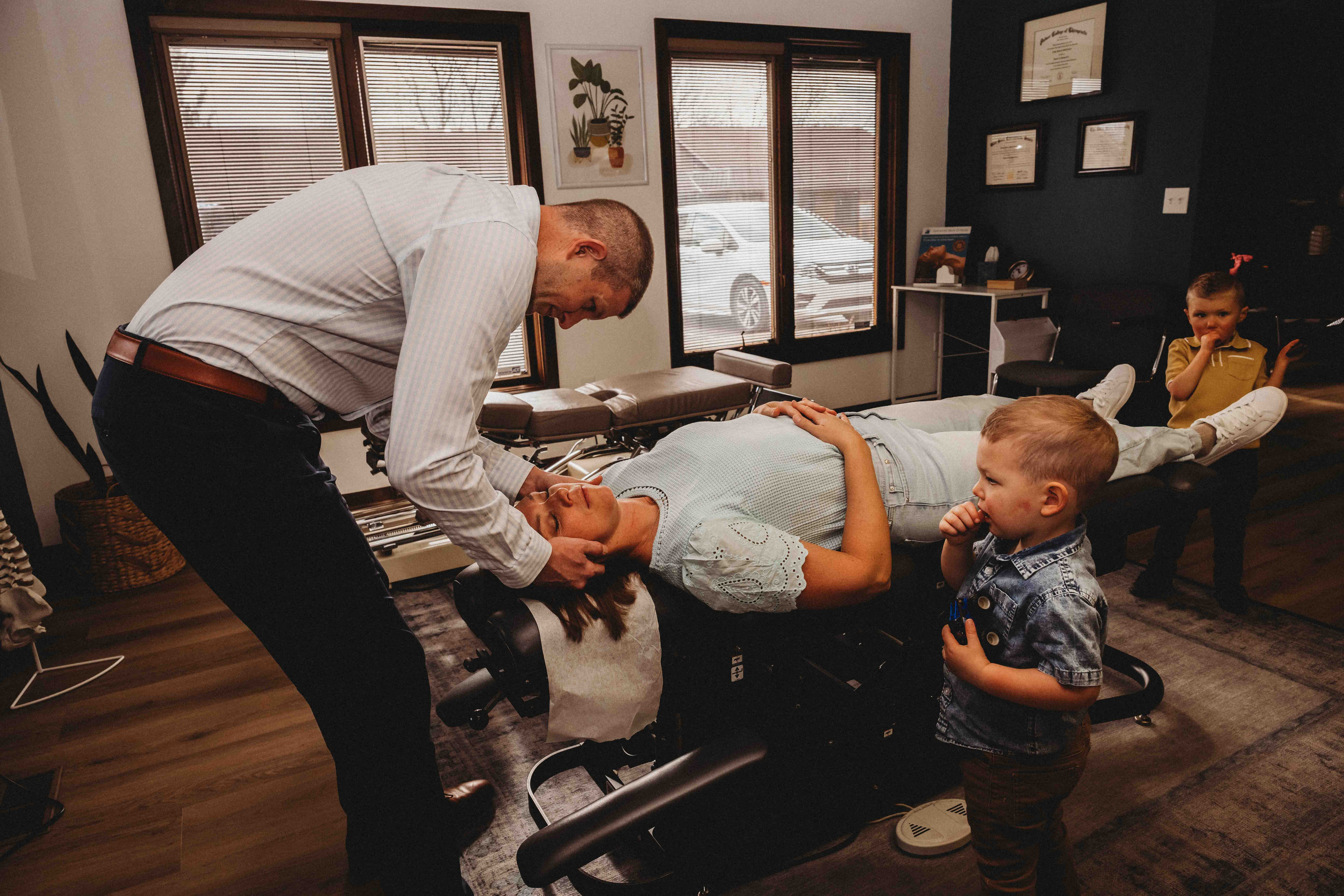 Physical therapist gently examining a patient’s neck and shoulder from behind