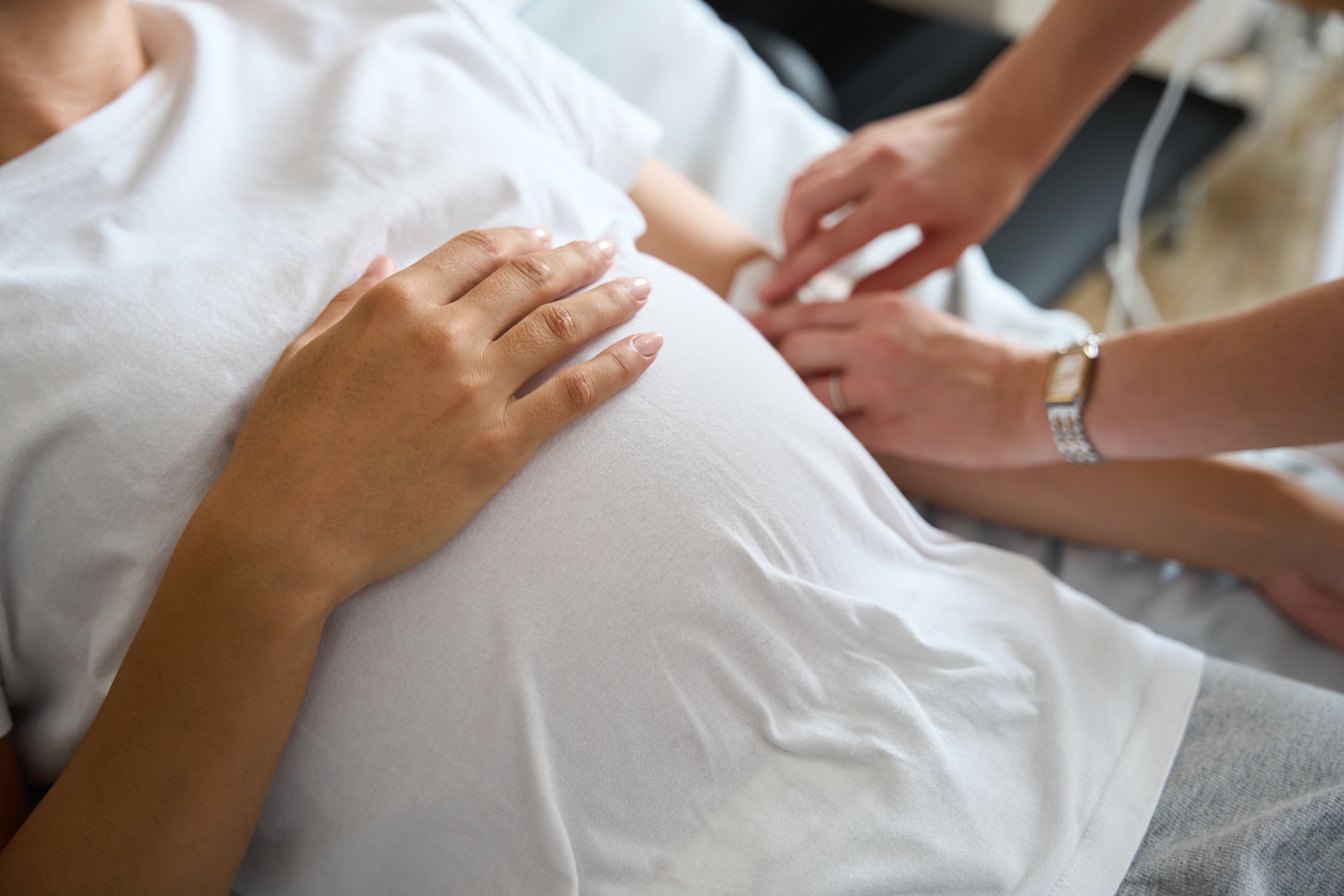 Physical therapist gently examining a patient’s neck and shoulder from behind