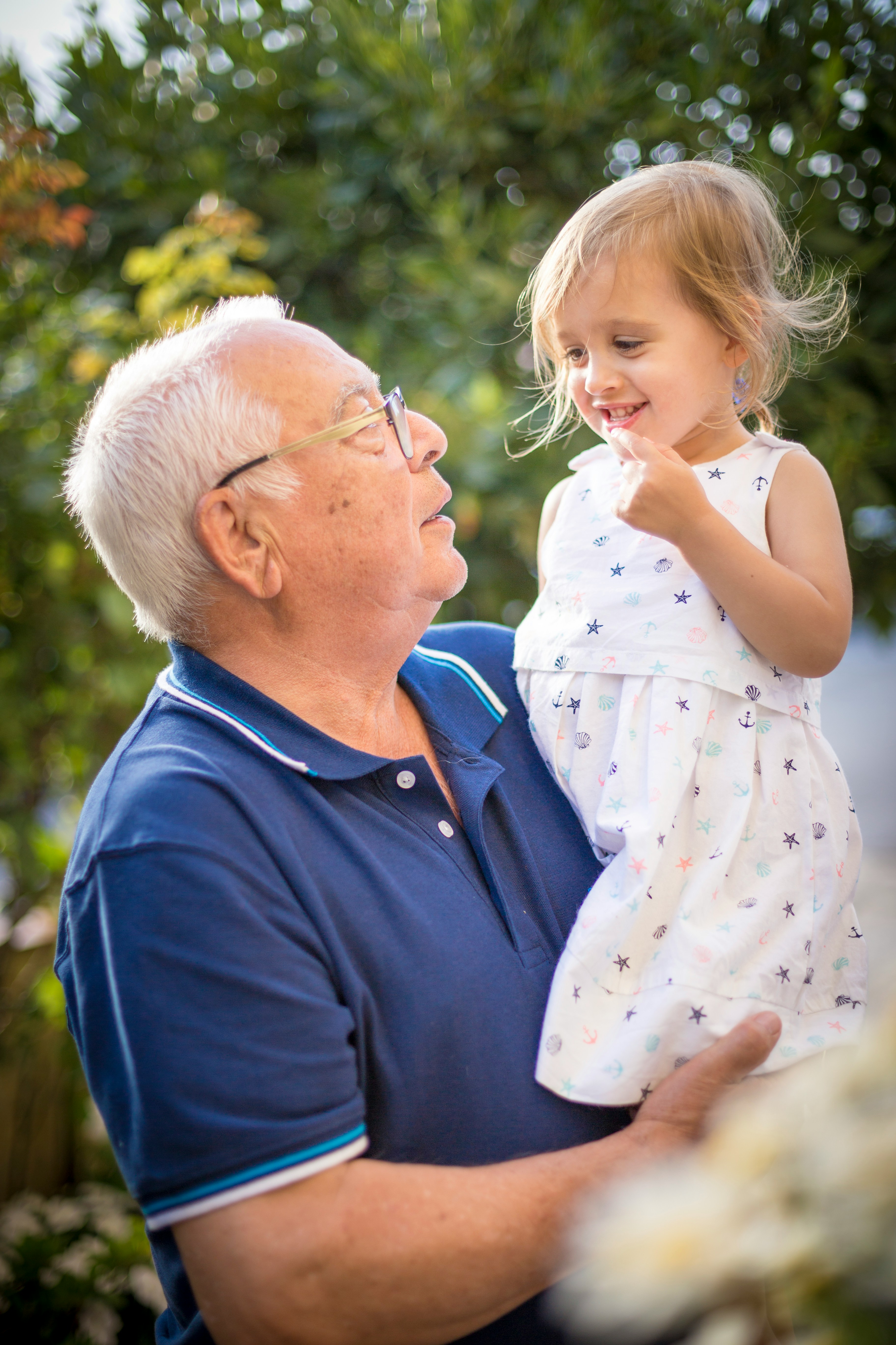 Elderly man holding a smiling young girl outdoors