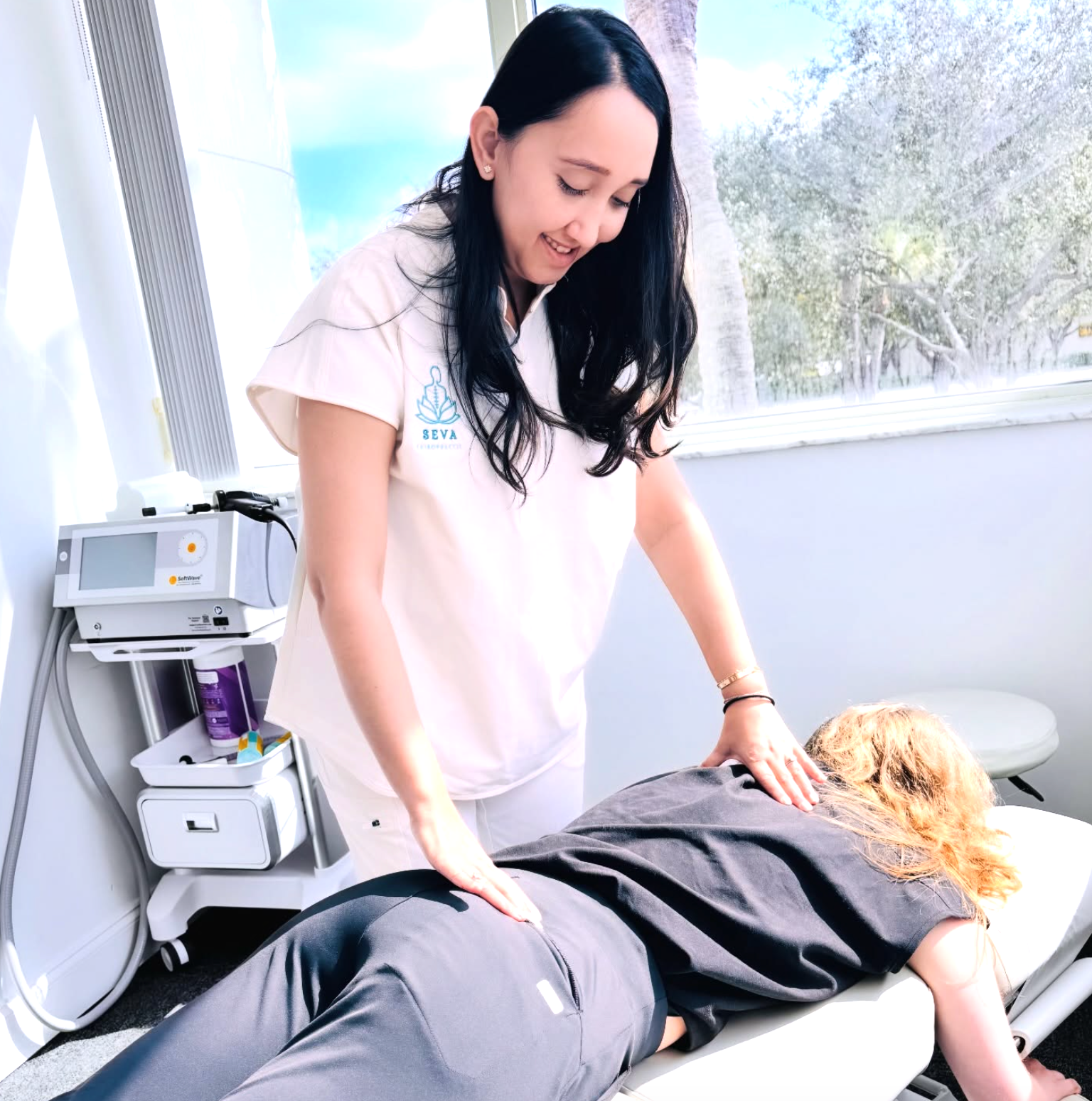 Chiropractor performing therapy on a patient lying face down on a treatment table.