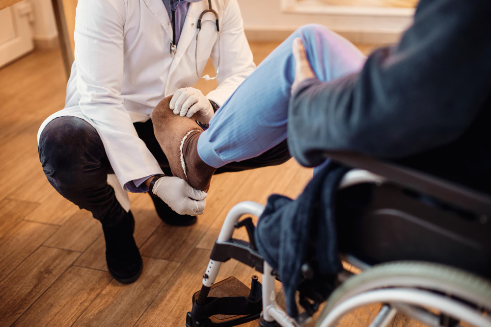 Doctor examining a patient's injured leg while the patient sits in a wheelchair.