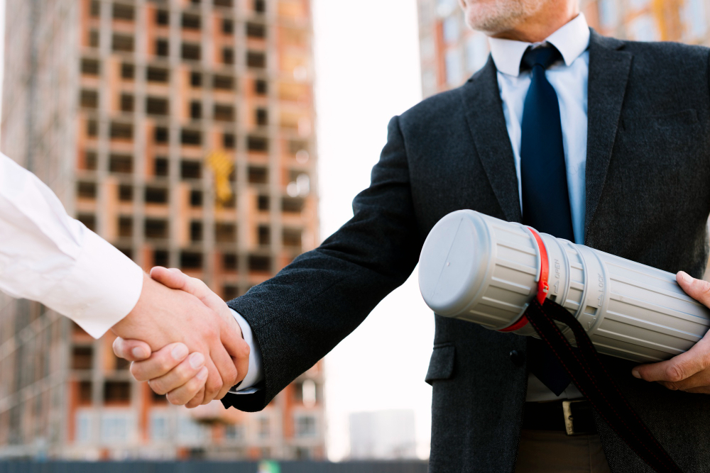 Two professionals shaking hands at a construction site.