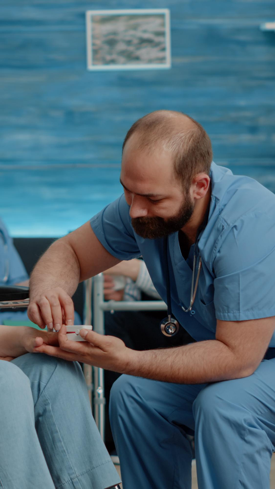 Medical professional in blue scrubs attending to a patient in a healthcare setting.