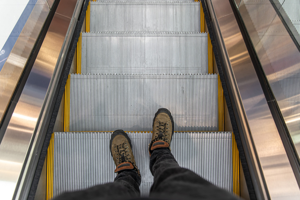 Person wearing brown shoes standing on an escalator