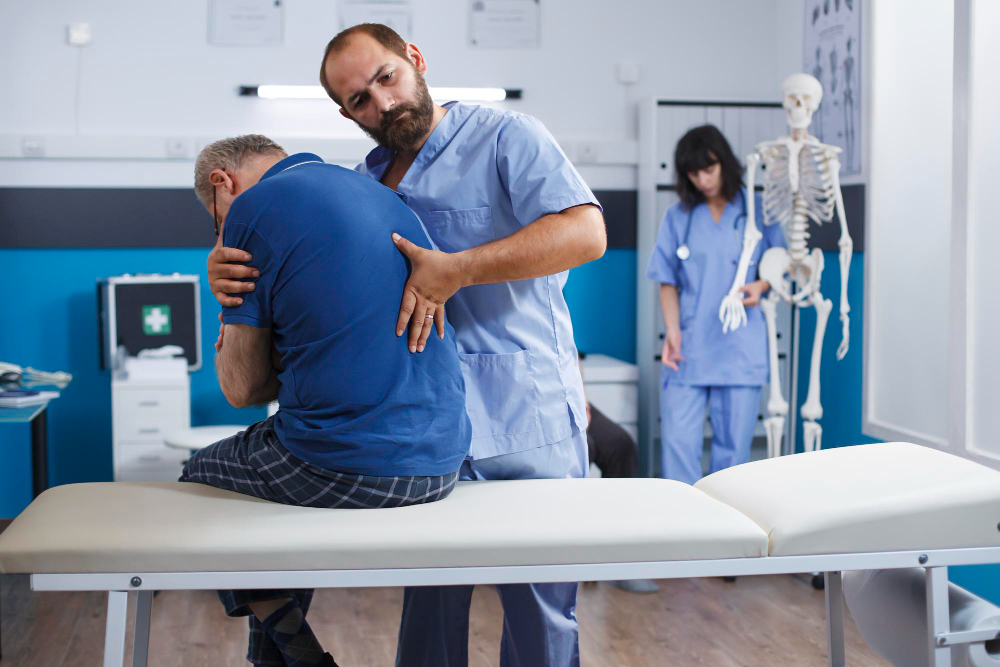 Physiotherapist examining a patient's back in a medical clinic.