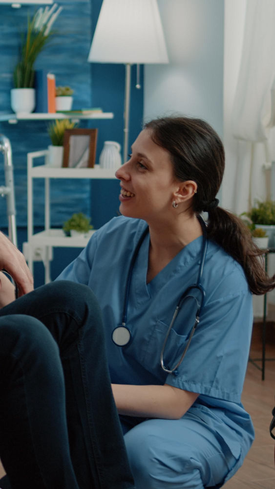 Healthcare professional in blue scrubs smiling and interacting with a patient.