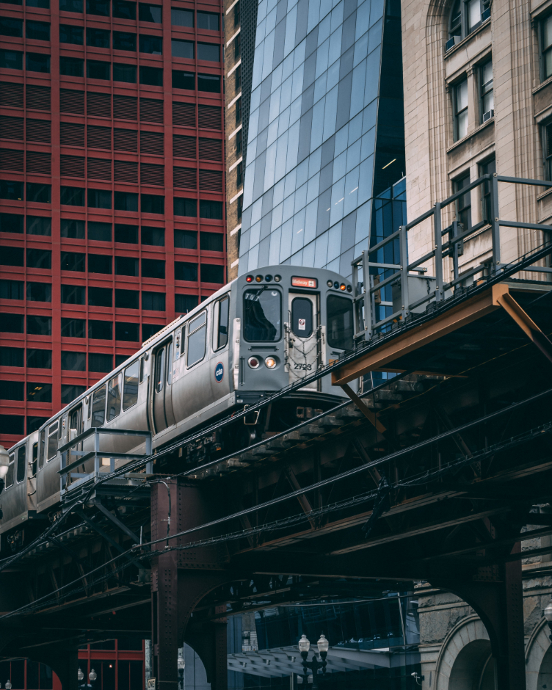 Elevated train passing through an urban area with modern and historic buildings.