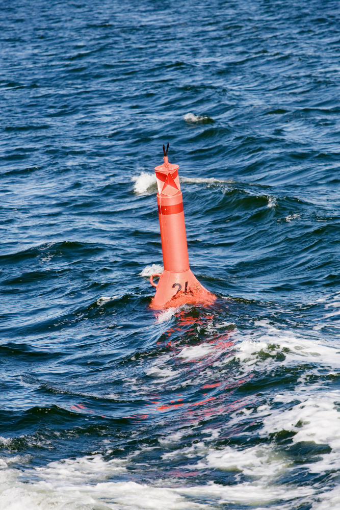 Red buoy floating in the ocean with waves surrounding it