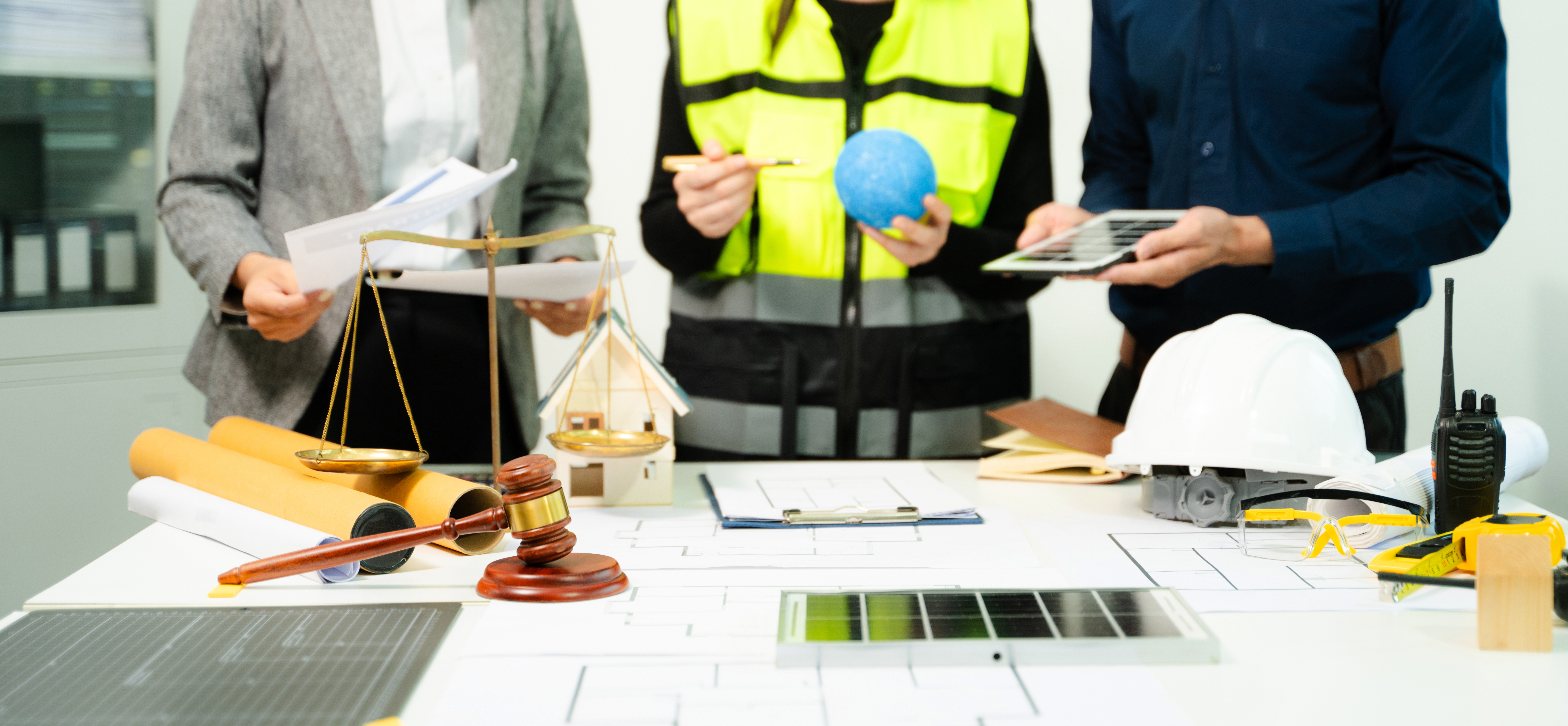 People signing documents at a table with a gavel, possibly in a legal setting.
