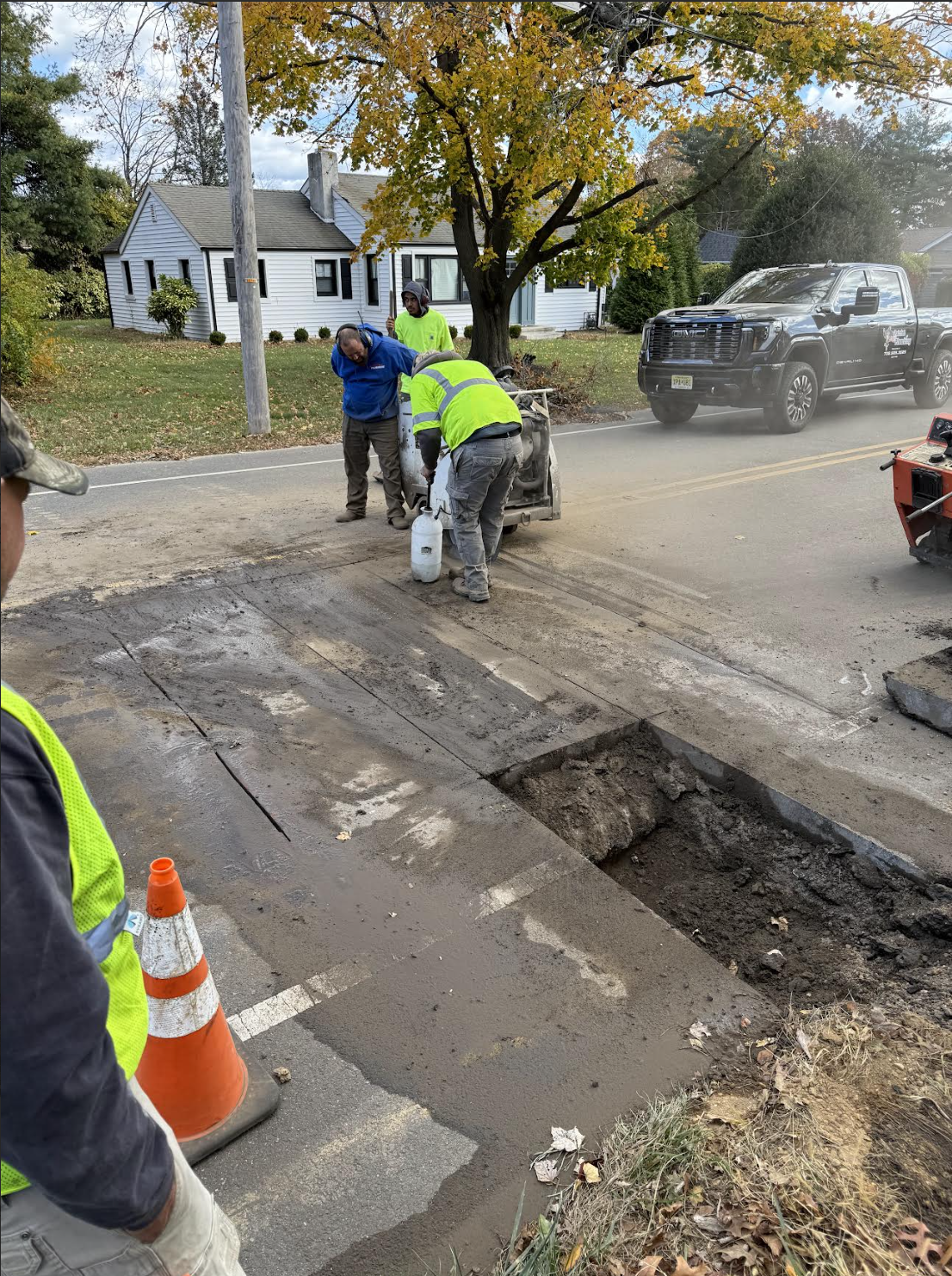 Workers repairing a road with construction equipment and traffic cones