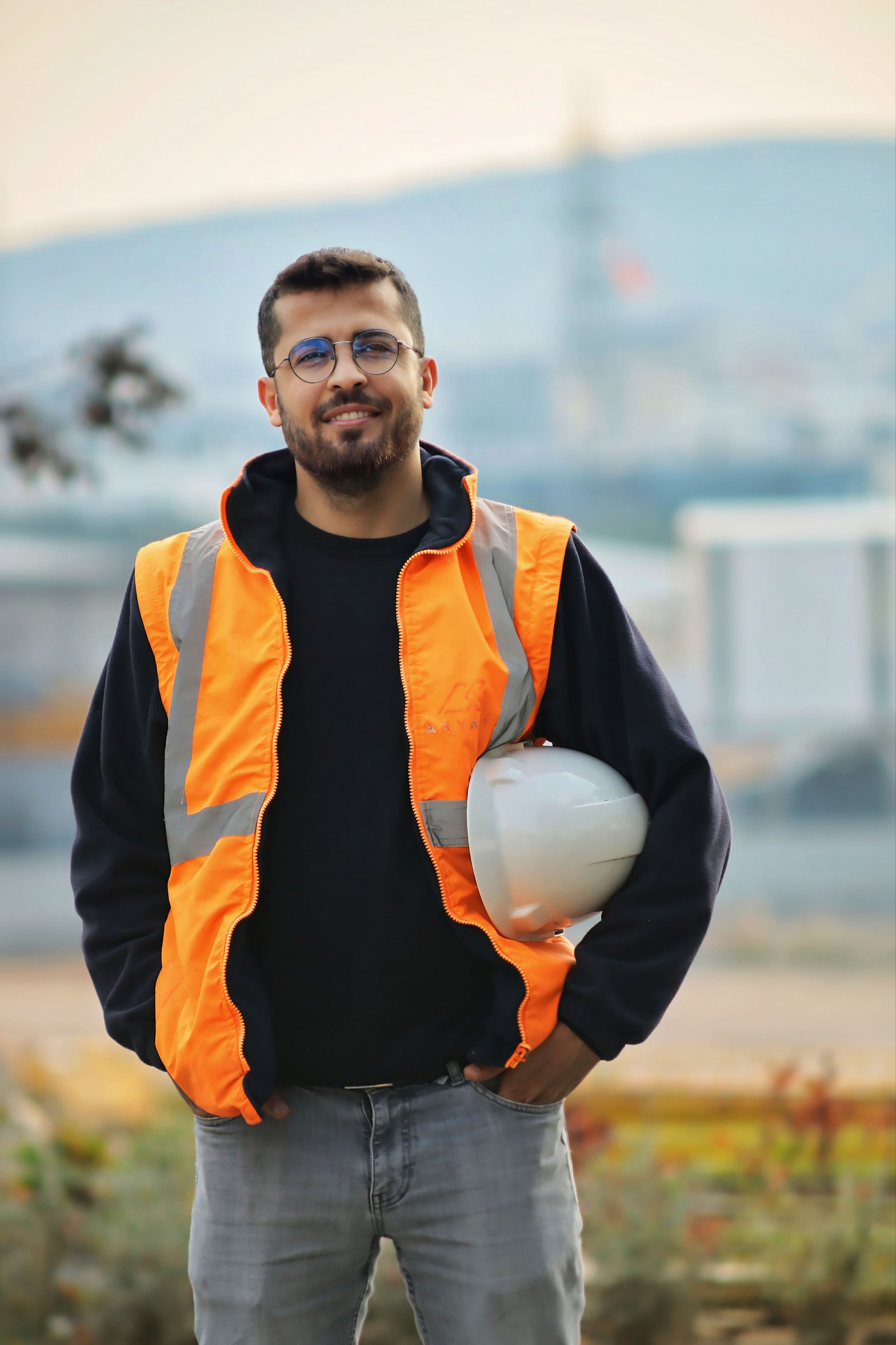 Construction worker wearing an orange safety vest holding a hard hat