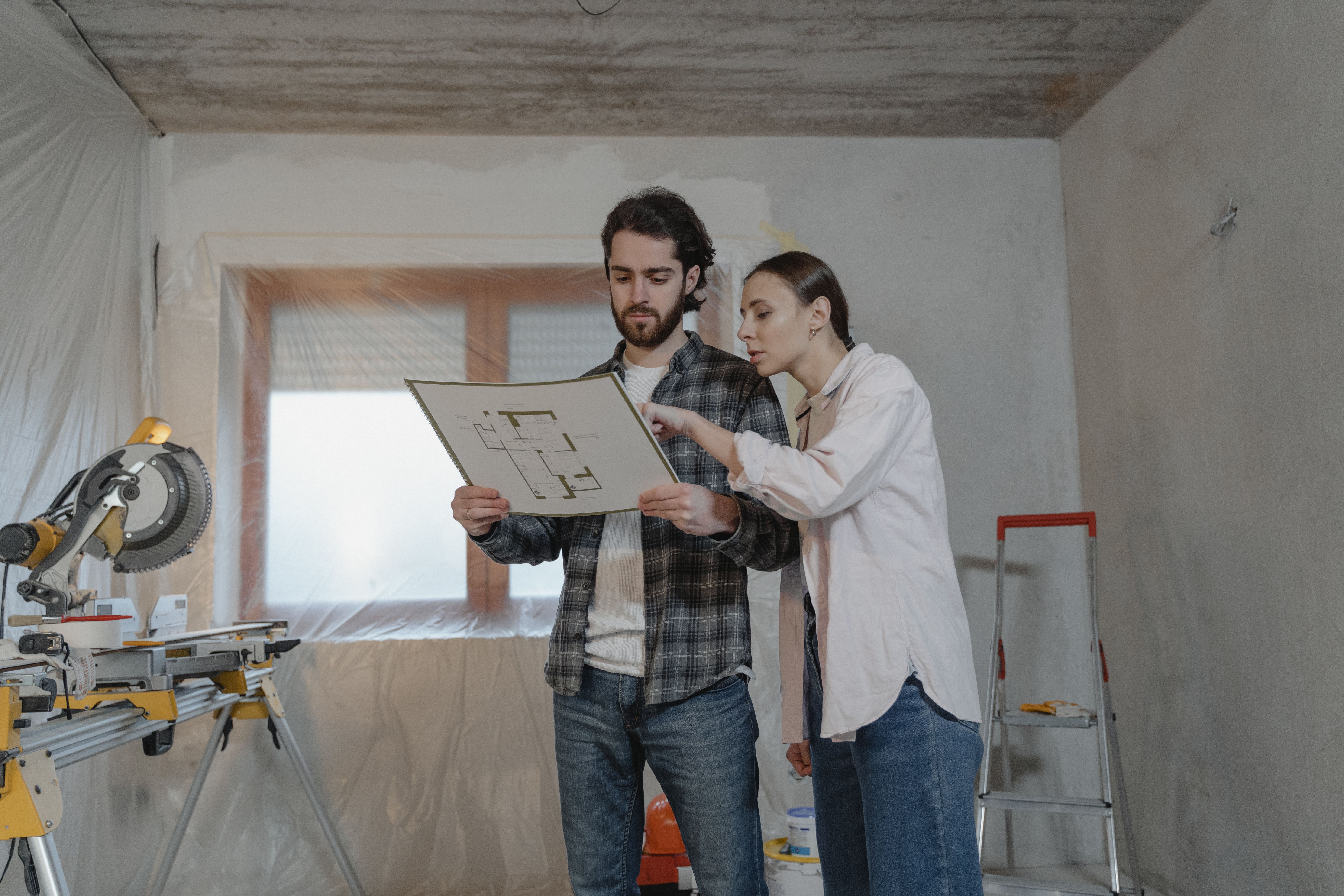 Two people reviewing a floor plan in a construction site.