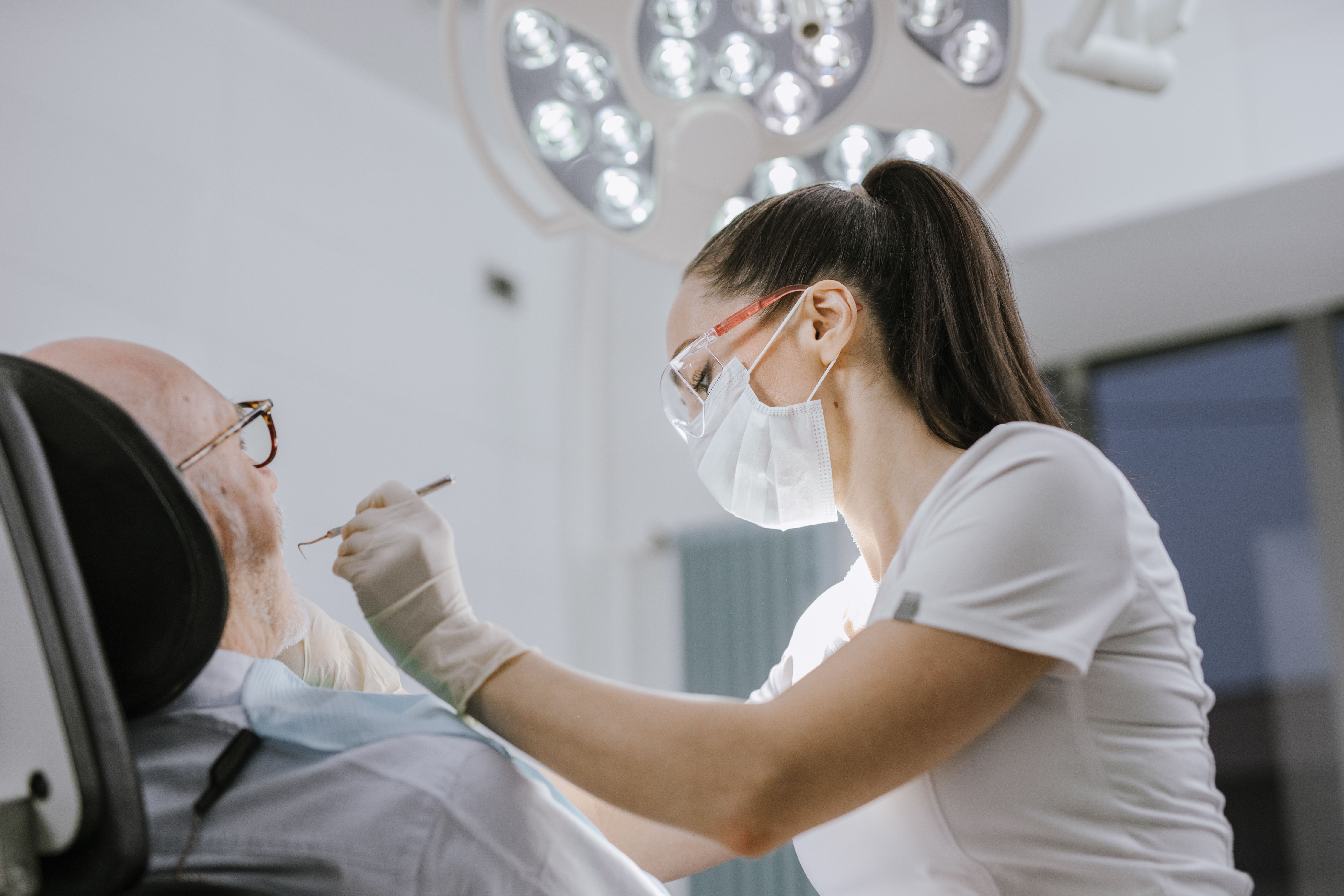 Dentist examining a patient's teeth under a bright light in a dental clinic