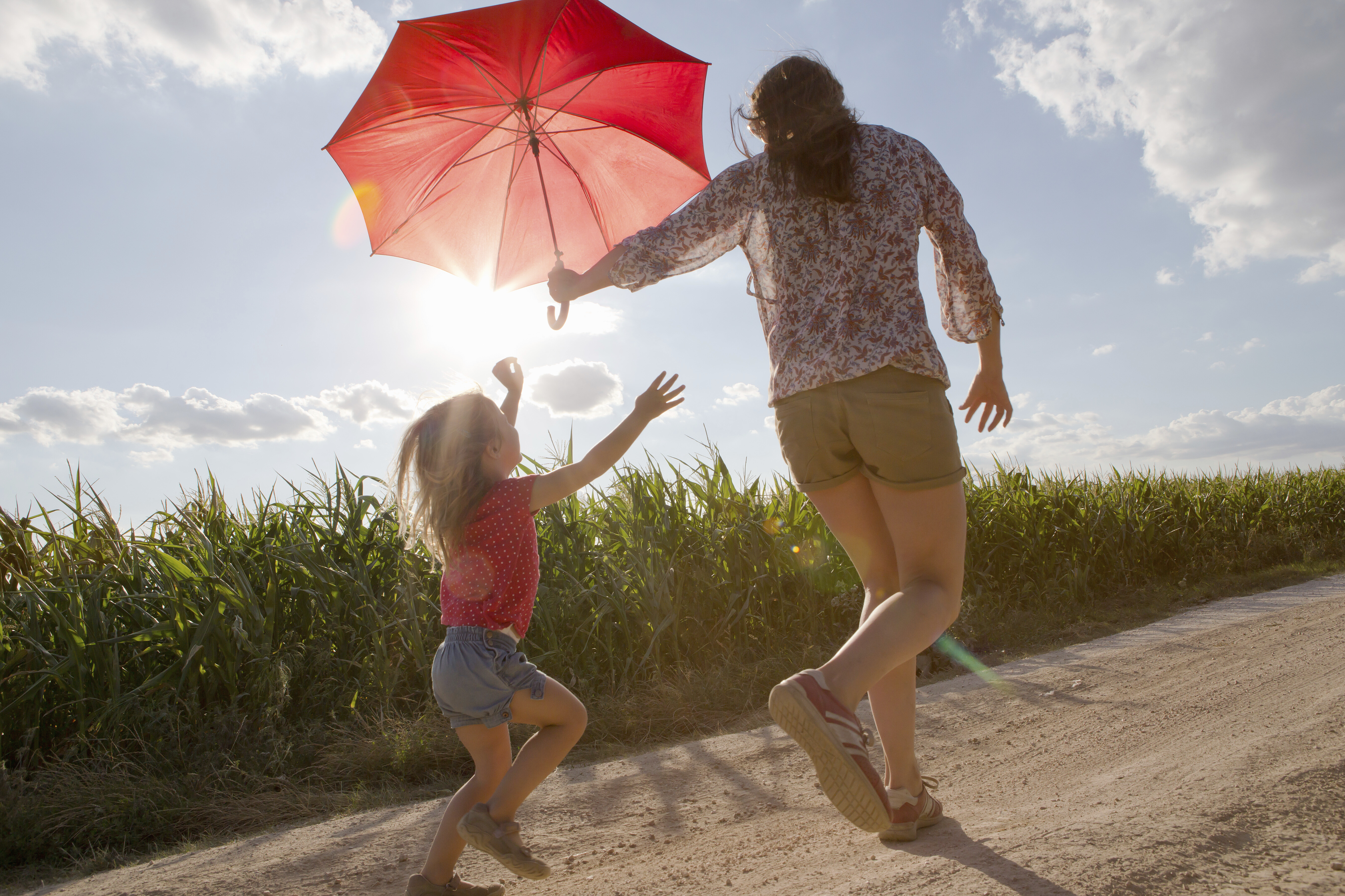 Smiling family of four crouching on a walkway in a green suburban yard outside a house