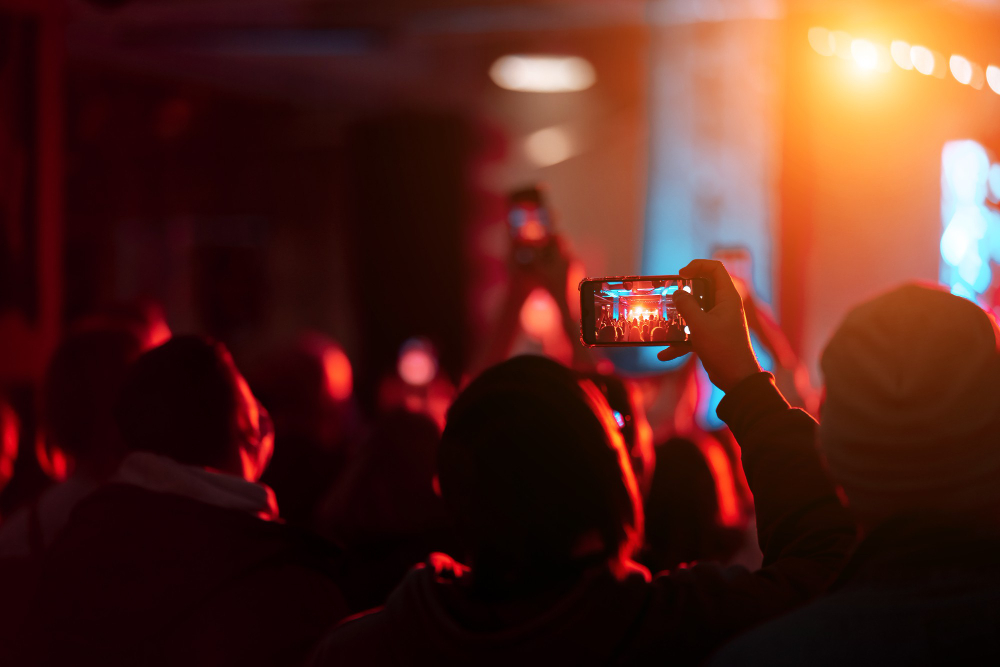 Audience capturing a live event on smartphones with vibrant lighting